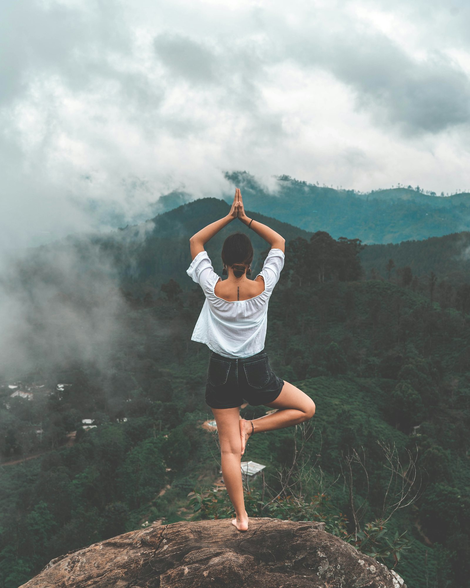 Persona practicando yoga frente a montañas con niebla