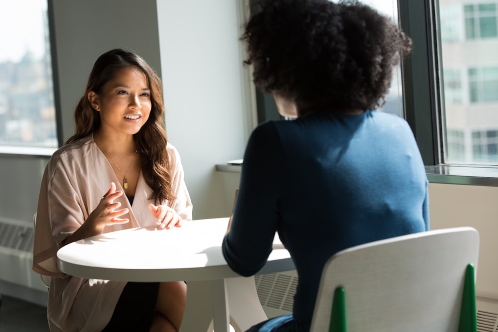 Dos personas conversando en una sesión de terapia junto a una ventana